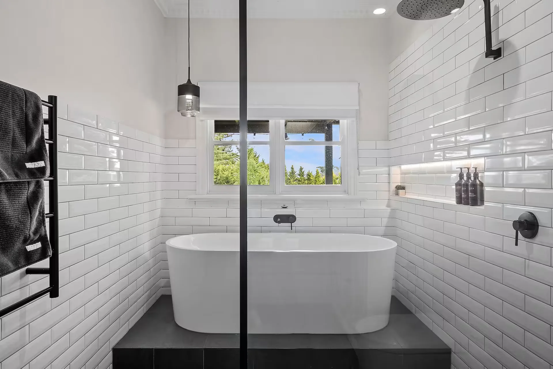 Gracemont’s freestanding soaking bath beneath the window, with white tiles and black fittings