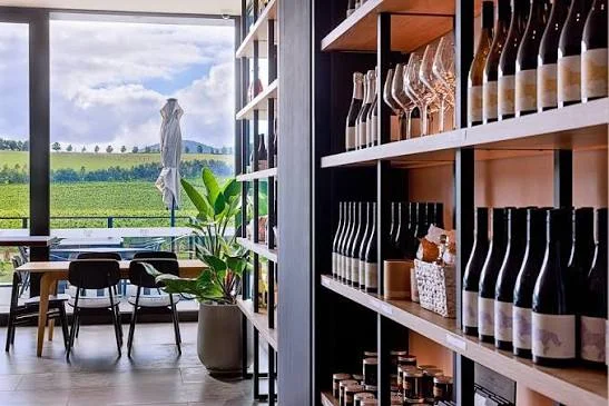 Wine bottles and glasses at Helen and Joey Estate with vineyard views through the window
