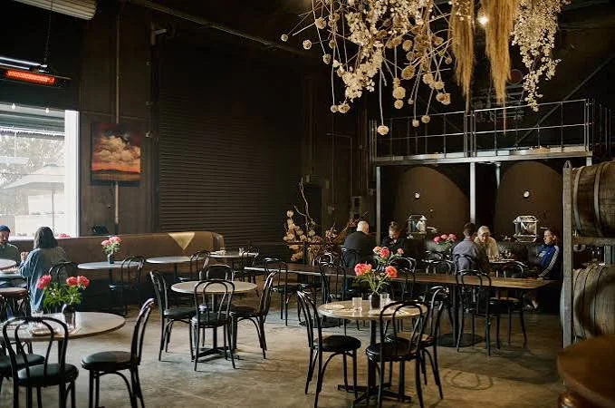 Tables, flowers and wine barrels inside Jayden Ong Winery and Cellar Bar