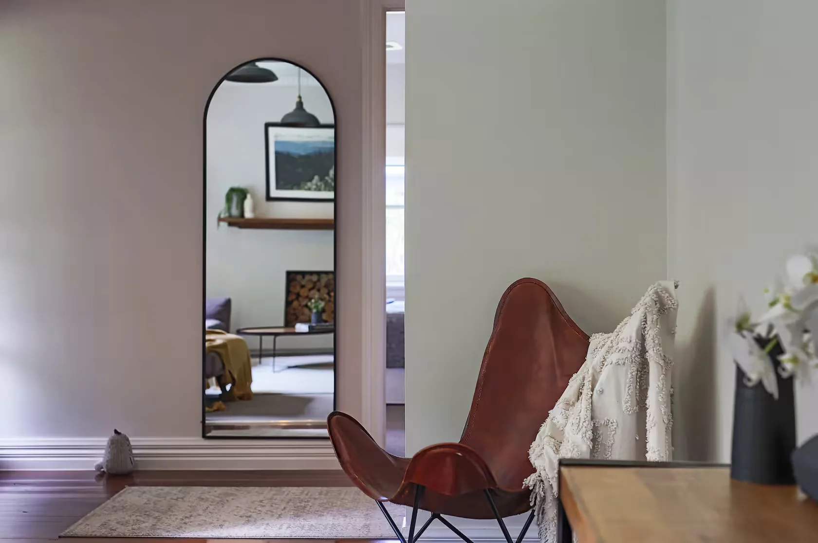 Leather chair and textured throw beside an arched mirror at Gracemont