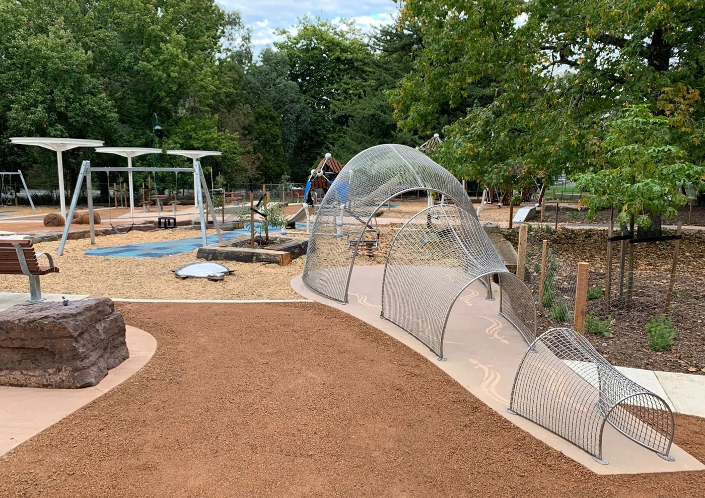 Playground beneath leafy trees at Queens Park